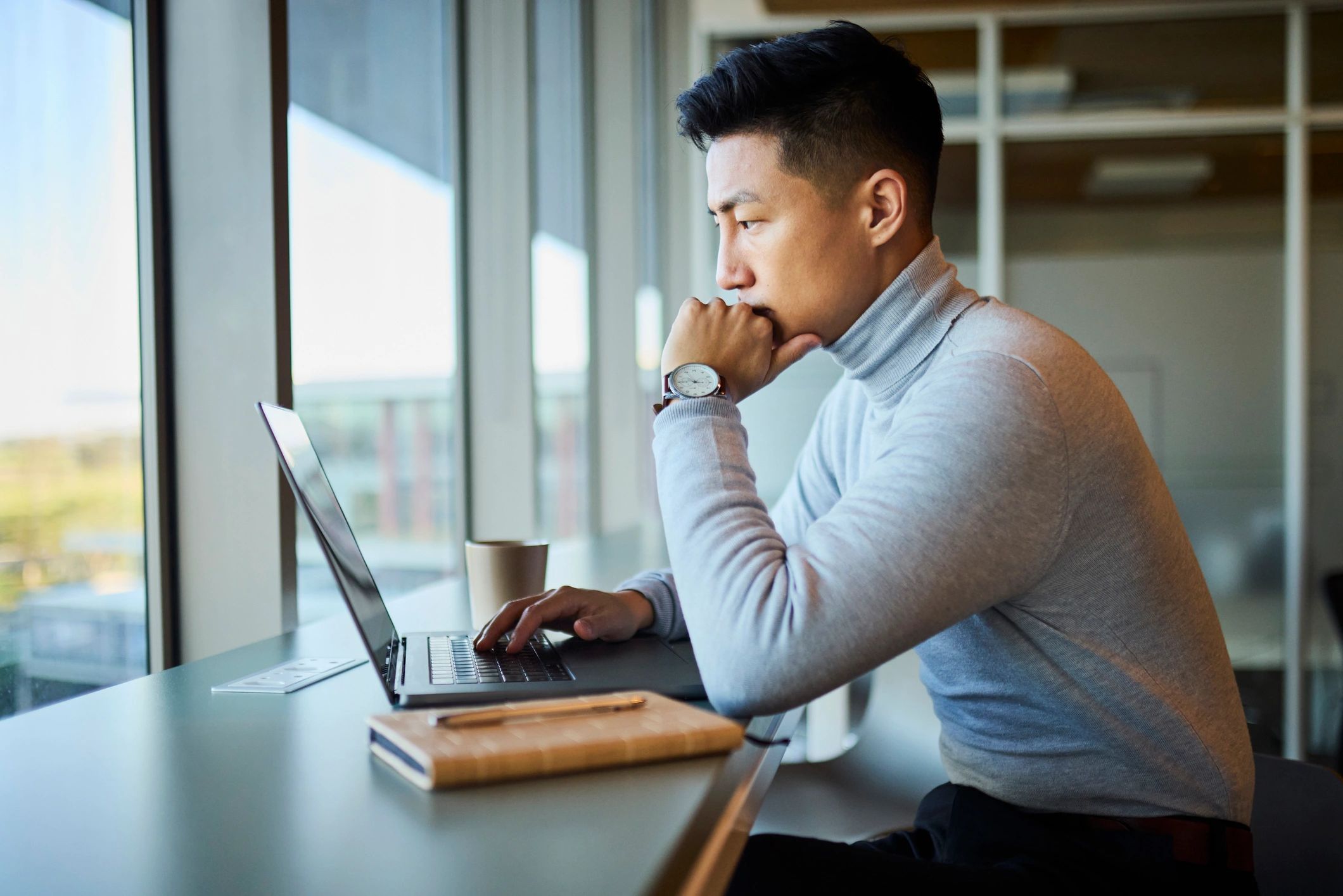 Consultant working thoughtfully on a laptop in a modern office